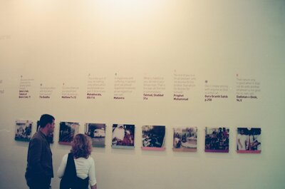 A couple reading faith-tradition quotes on a gallery wall — London, England (August 2000)