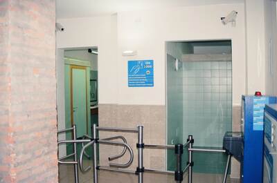 A pay-toilet entrance with turnstiles and a Lire 1000 sign — Italy, Italy (7-10 June 2000)