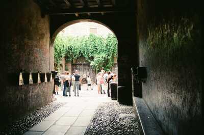 A sunlit courtyard through a stone arch — Verona