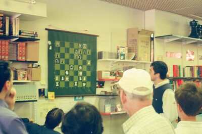 Spectators watching a demonstration board at the chess shop — London, England (August 2000)