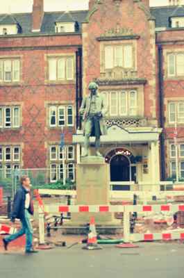 A statue outside a red-brick civic building amid street works — England, England (August 2000)
