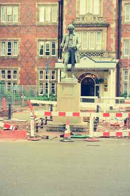 A statue outside a red-brick civic building with road works — England, England (August 2000)