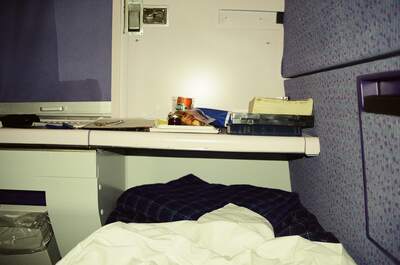 A made bunk and lamp-lit desk in a sleeper train cabin — On the sleeper to Glasgow, Scotland (20-25 July 2000)