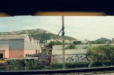 Hills and graffitied warehouses from a moving train window — Southern France, France (13-20 July 2000)