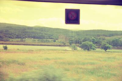 A castle ruin in farmland glimpsed from the train — Scottish Highlands, Scotland (late July 2000)